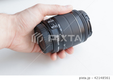 Hand holding camera lens on white background Hand holding camera lens on white background 42148561