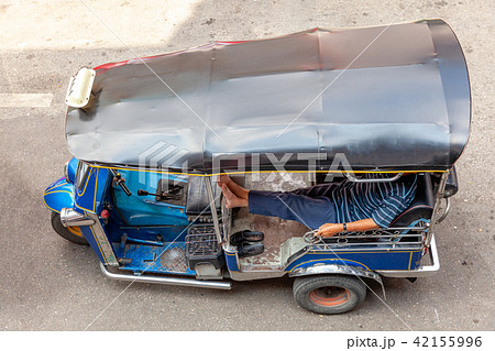 A tuk-tuk driver waits for customers on the street 42155996