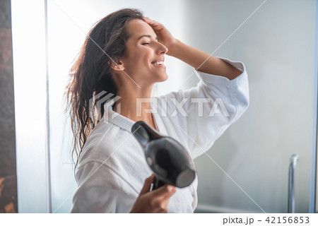 Cheerful female drying hair with gadget Cheerful female drying hair with gadget 42156853