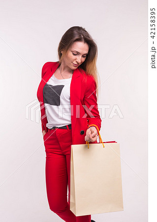Tender young woman with shopping bags in red suit is posing on white background. 42158395