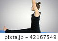 Young woman stretching leg on mat, practicing yoga on white background 42167549