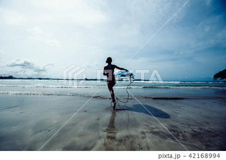 woman surfer with surfboard running on beach woman surfer with surfboard running on beach 42168994