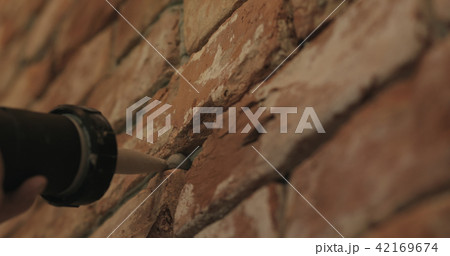 Slow motion closeup of worker filling seam between bricks with mortar from sealant gun Slow motion closeup of worker filling seam between bricks with mortar from sealant gun 42169674