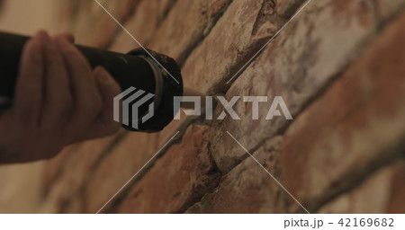 Slow motion closeup of worker filling seam between bricks with mortar from sealant gun 42169682