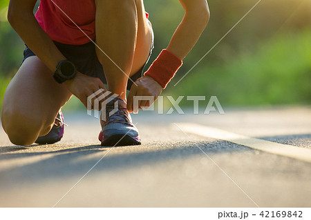 runner tying shoelace before run on forest trail 42169842