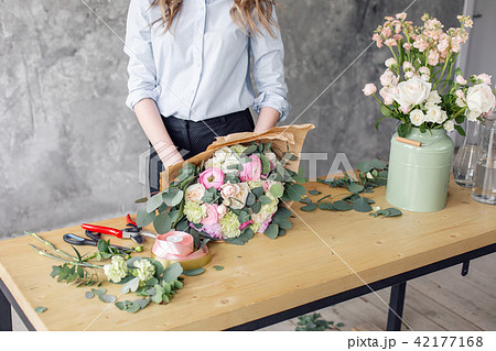 Woman florist creating beautiful bouquet in flower shop. Working in flower shop. Girl assistant or Woman florist creating beautiful bouquet in flower shop. Working in flower shop. Girl assistant or 42177168