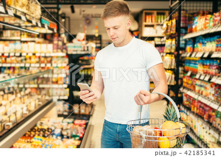 Male customer uses mobile phone in supermarket 42185341