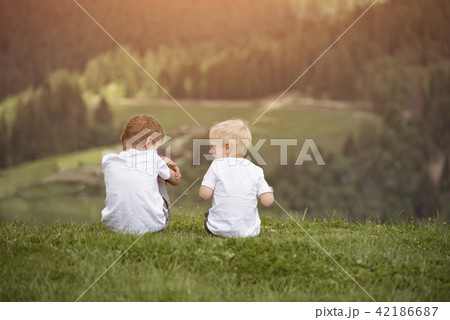 Two boys sit on a hill and have fun. Back view 42186687