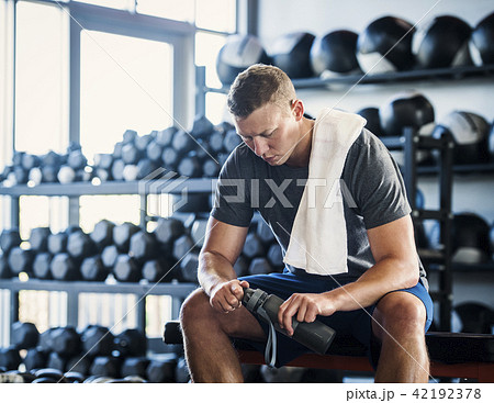 Mid adult man with towel and bottle in gym Mid adult man with towel and bottle in gym 42192378