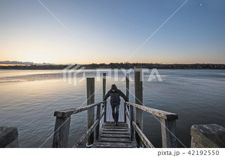 Man standing on pier at dawn 42192550