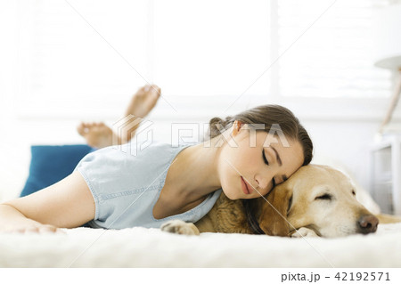 Woman lying on bed with dog 42192571
