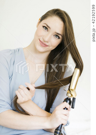 Woman using curling iron Woman using curling iron 42192599