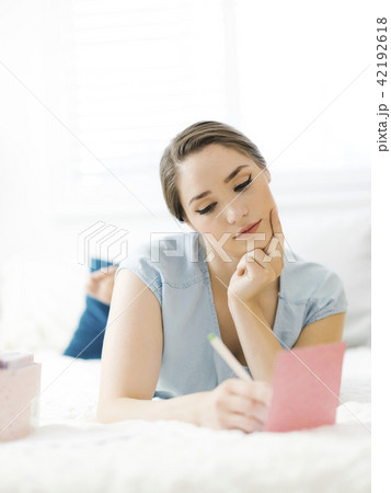 Woman writing in card on bed 42192618