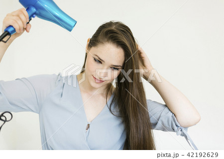 Woman using hair dryer Woman using hair dryer 42192629