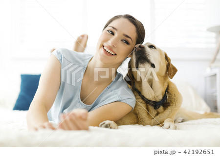 Woman lying on bed with dog Woman lying on bed with dog 42192651