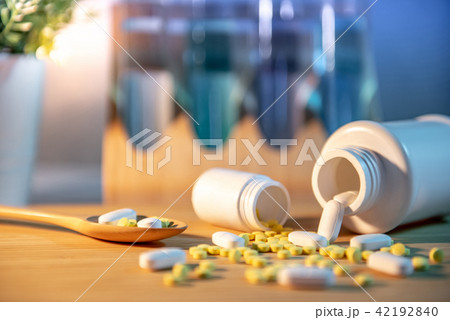 Pills spilling out of pill bottles on wooden table Pills spilling out of pill bottles on wooden table 42192840