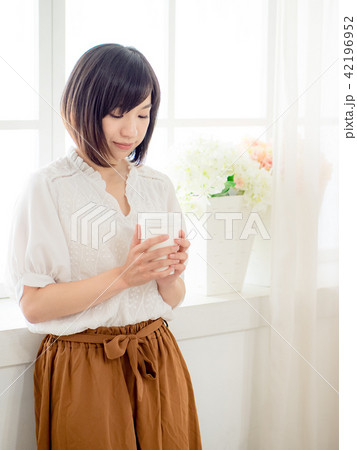 young woman standing in front of window young woman standing in front of window 42196952