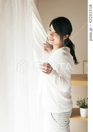 グラスを持ちカーテンを開ける女性 42201518