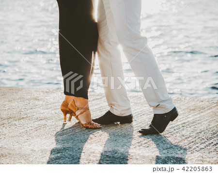 Young attractive couple dancing latin bachata near sea or ocean. Sunlight background. Summer time 42205863