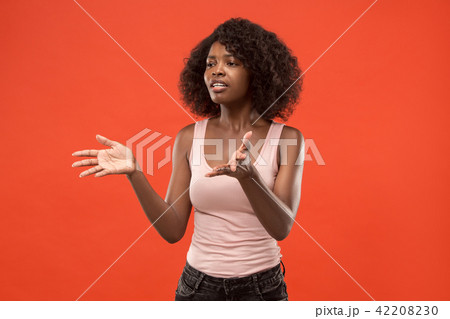 Beautiful female half-length portrait isolated on red studio backgroud. The young emotional 42208230