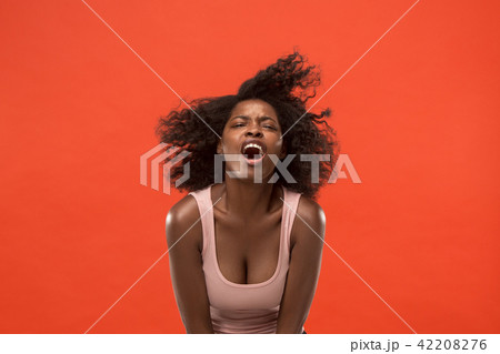 The young emotional angry woman screaming on red studio background 42208276