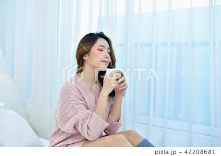 Winter Concept. Beautiful woman is relaxing in a white bedroom. Winter Concept. Beautiful woman is relaxing in a white bedroom. 42208681