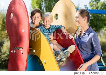 Family playing on adventure playground, children chuting chute 42208869