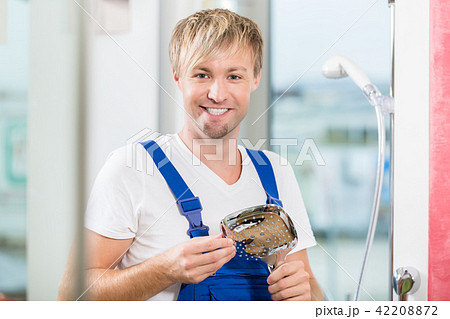 Portrait of a cheerful maintenance worker holding a faucet Portrait of a cheerful maintenance worker holding a faucet 42208872