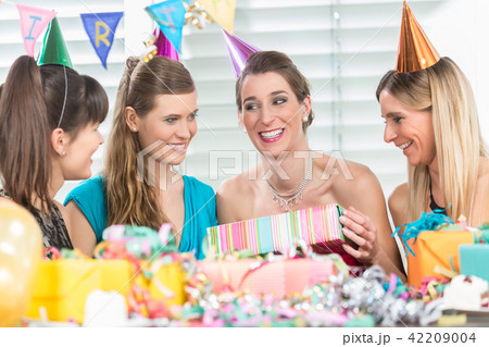 Cheerful woman holding a gift box during a surprise birthday party 42209004