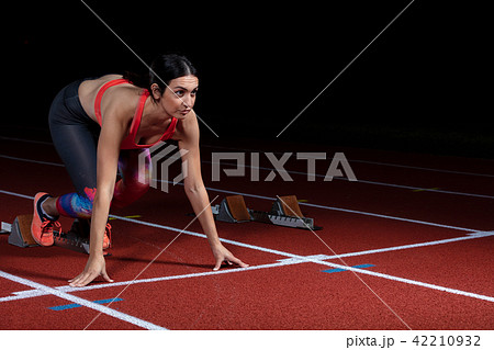 woman sprinter leaving starting blocks on the athletic track. exploding start on stadium with woman sprinter leaving starting blocks on the athletic track. exploding start on stadium with 42210932
