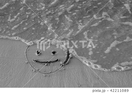On the sand drawn a smiley face and a wave washes On the sand drawn a smiley face and a wave washes 42211089