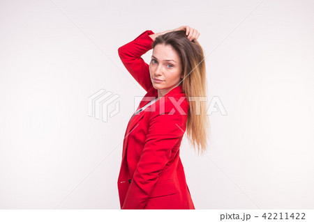 portrait of young beautiful woman posing in red suit with hand above. 42211422