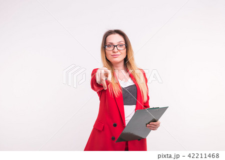 Pointing stylish business lady with documents in red fashionable suit and glasses on white 42211468