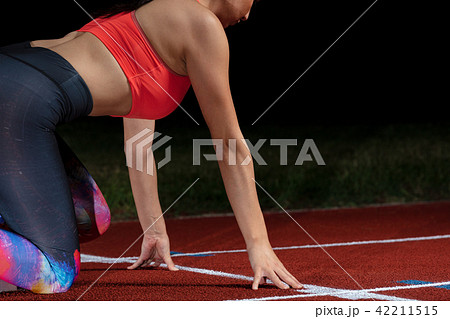 woman sprinter leaving starting blocks on the athletic track. exploding start on stadium with 42211515