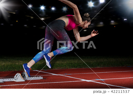 woman sprinter leaving starting blocks on the athletic track. exploding start on stadium with 42211537
