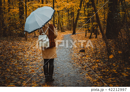 Girl with umbrella on the autumnal colorful forest path 42212997