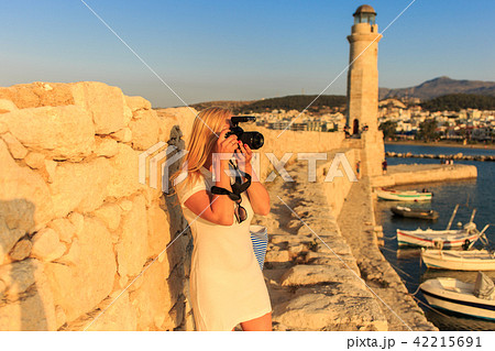 Traveler woman photographer with professional camera takes shot of Rethymno,Crete, Greece. Traveler woman photographer with professional camera takes shot of Rethymno,Crete, Greece. 42215691