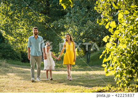 Caring parents holding hands of daughter while walking together in the park 42225837