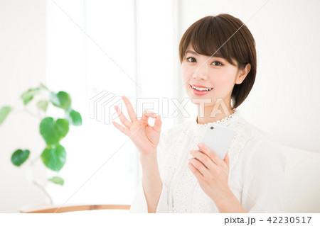 スマホを持ってオッケーサインをする女性 42230517