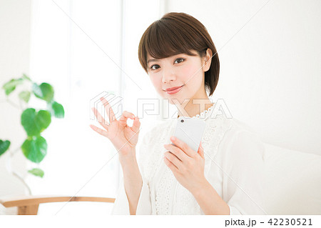 スマホを持ってオッケーサインをする女性 42230521