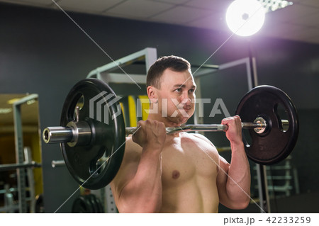 Handsome power athletic man with barbell. Strong bodybuilder with six pack, perfect abs, shoulders 42233259
