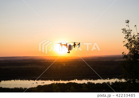 silhouette of drone, quadrocopter with photo camera flying in the sky. 42233485