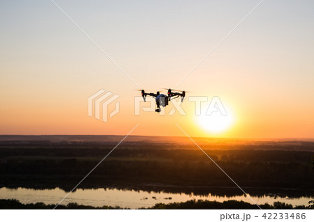 silhouette of drone, quadrocopter with photo camera flying in the sky. 42233486