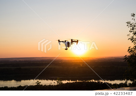 silhouette of drone, quadrocopter with photo camera flying in the sky. silhouette of drone, quadrocopter with photo camera flying in the sky. 42233487
