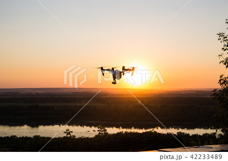 silhouette of drone, quadrocopter with photo camera flying in the sky. silhouette of drone, quadrocopter with photo camera flying in the sky. 42233489