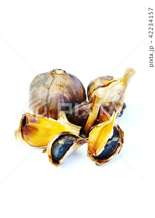 健康食品ヘルシー素材・熟成黒ニンニクの褐色の鱗茎（ニンニク球）と黒い鱗片複数・白バック縦位置 42234157