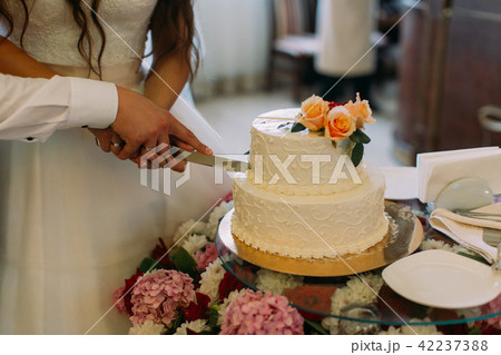 The hands of the newlywed couple cutting their first piece of the wedding cake. 42237388
