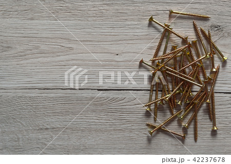 Yellow screws are laid out on wooden background Yellow screws are laid out on wooden background 42237678
