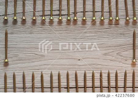 Yellow screws in two rows on wooden background 42237680