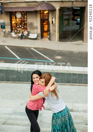 Two women hugging in the street 42240118